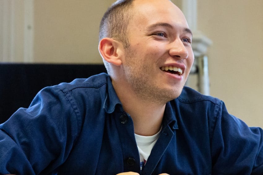 Isaac in rehearsals – close up photo of Isaac as he leans against the top of lockers.