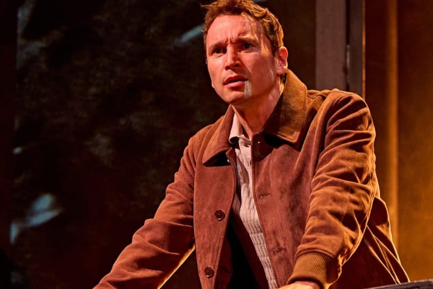 A production image from ‘Don’t Look Now.’ John stands at the top of some stairs, resting his hands on the metal railings in front of him. He looks confused at something he has seen.