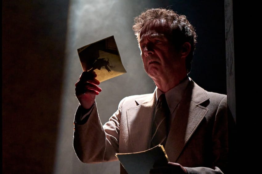 A production image from ‘Don’t Look Now.’ A man stands in a spotlight, looking concerned as he looks at a piece of paper which he holds in his right hand.