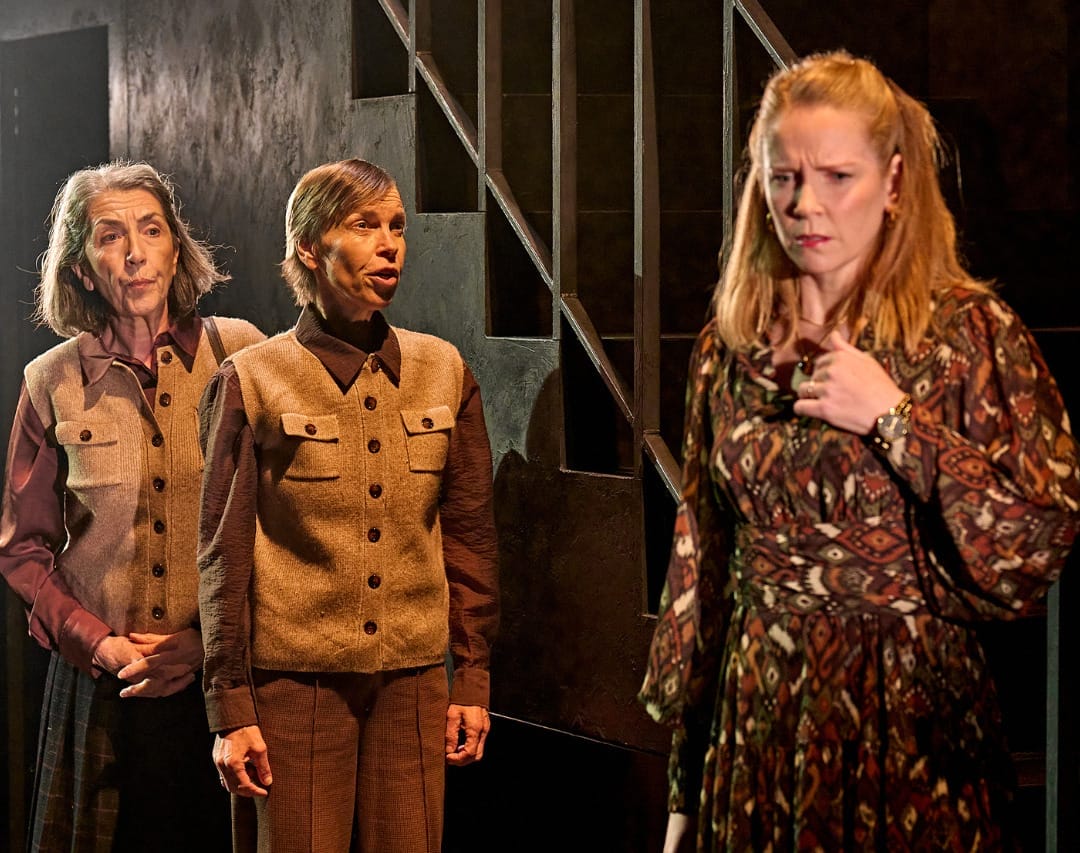 A production image from ‘Don’t Look Now.’ Laura expresses a sad emotion, holding one hand towards her chest. She has seemingly been told some sad or worrying news from the sisters, who stand to the left of her.